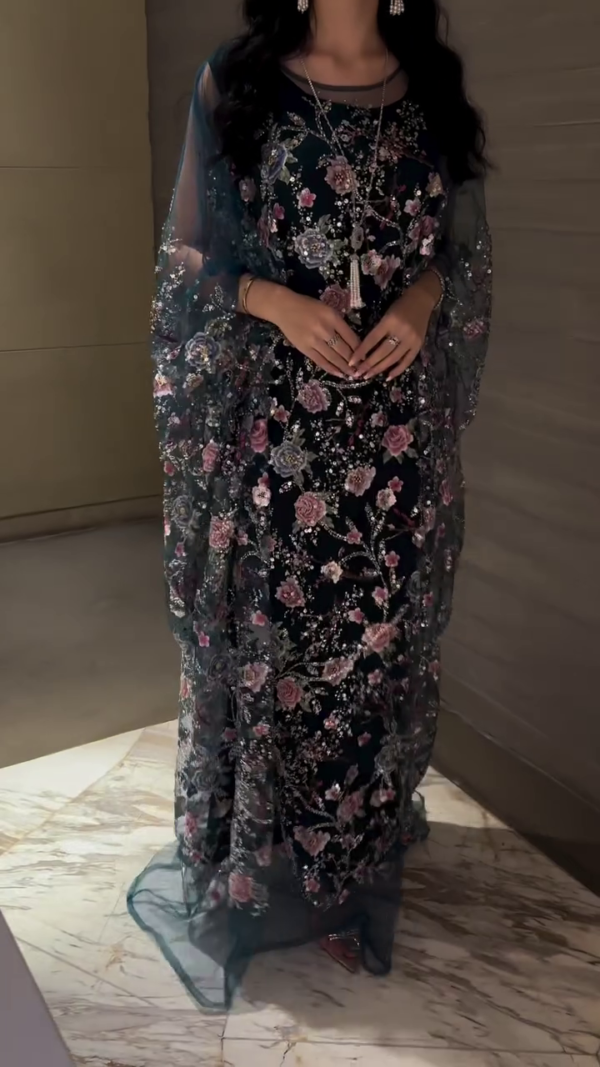 Black gown with crisscross straps, with attached embellished cape.